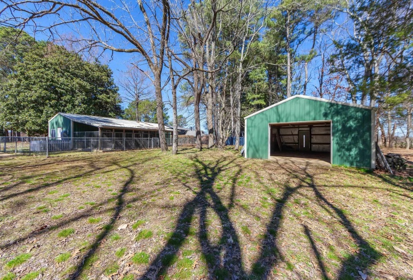 View of yard featuring a garage, a pole building, fence, and an outdoor structure
