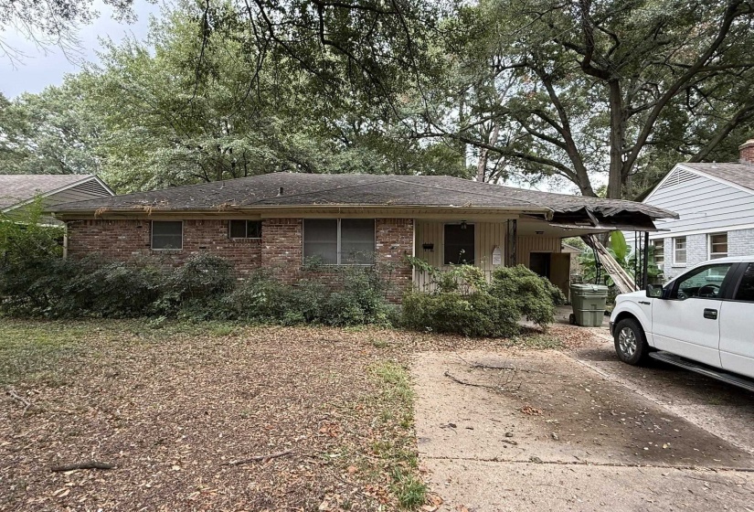 Brick exterior residence with a partial concrete driveway and mature trees