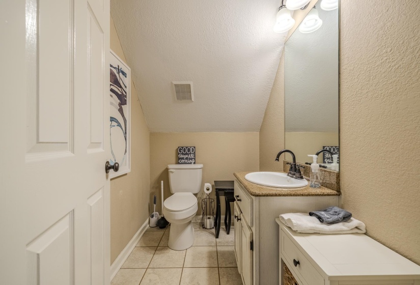 Bathroom featuring a white vanity with an undermount sink, granite-finish countertop, and dark-finish faucet