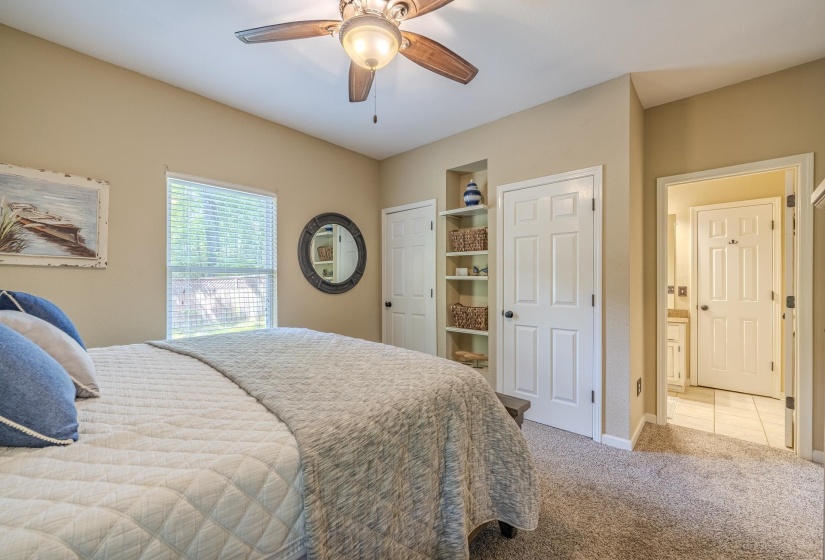 Carpeted room featuring a ceiling fan with integrated lighting, a window with blinds, and an integrated shelving unit