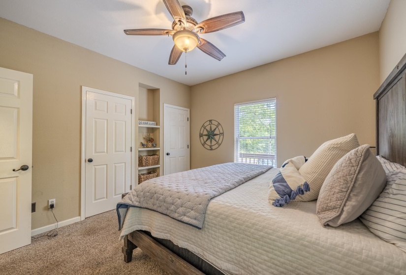 Carpeted bedroom featuring a wooden bed frame, ceiling fan with integrated lighting, white trim, and a window with horizontal blinds