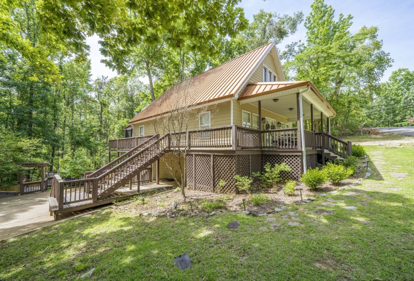 Elevated home featuring a covered front porch, an expansive deck with wood railing, and a durable metal roof