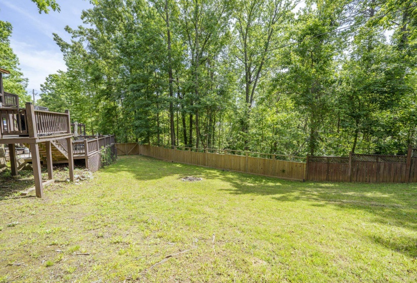 Expansive backyard featuring a lush lawn, privacy fencing, and a multi-level deck structure with railings