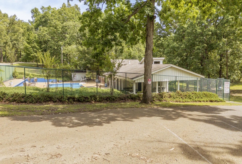 Recreational facility featuring a fenced swimming pool, poolside seating, and a single-story building with a covered patio