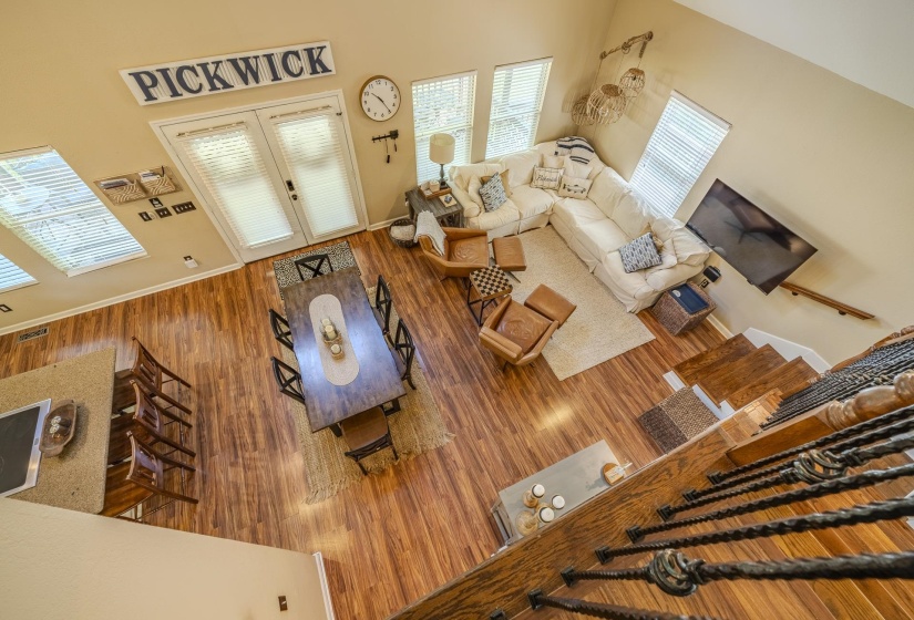 Open-concept living and dining area featuring wood-finish flooring throughout, abundant natural light from multiple windows, and a built-in kitchen island with seating