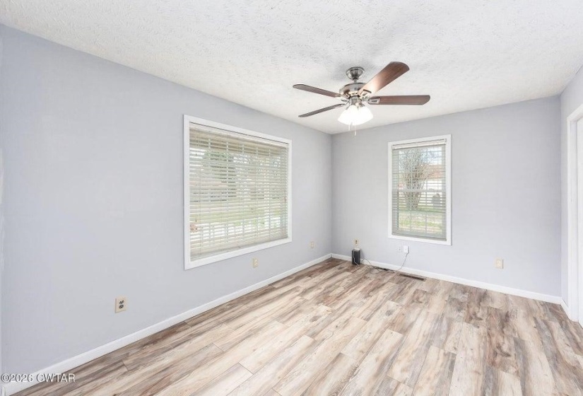 Empty room featuring light wood-style flooring, a textured ceiling, and a ceiling fan