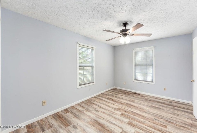 Unfurnished room with light wood-style flooring, a ceiling fan, and a textured ceiling