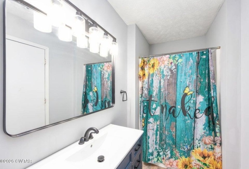 Bathroom featuring vanity, a textured ceiling, and a shower with curtain