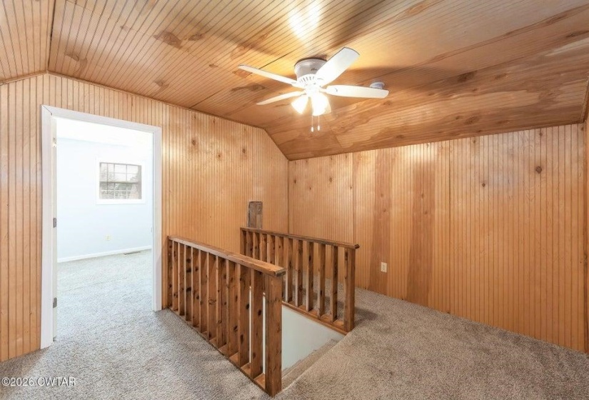 Corridor featuring an upstairs landing, wood walls, carpet flooring, and a vaulted wood ceiling