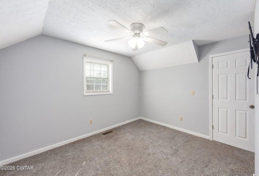 Bonus room featuring a textured ceiling, a ceiling fan, and carpet