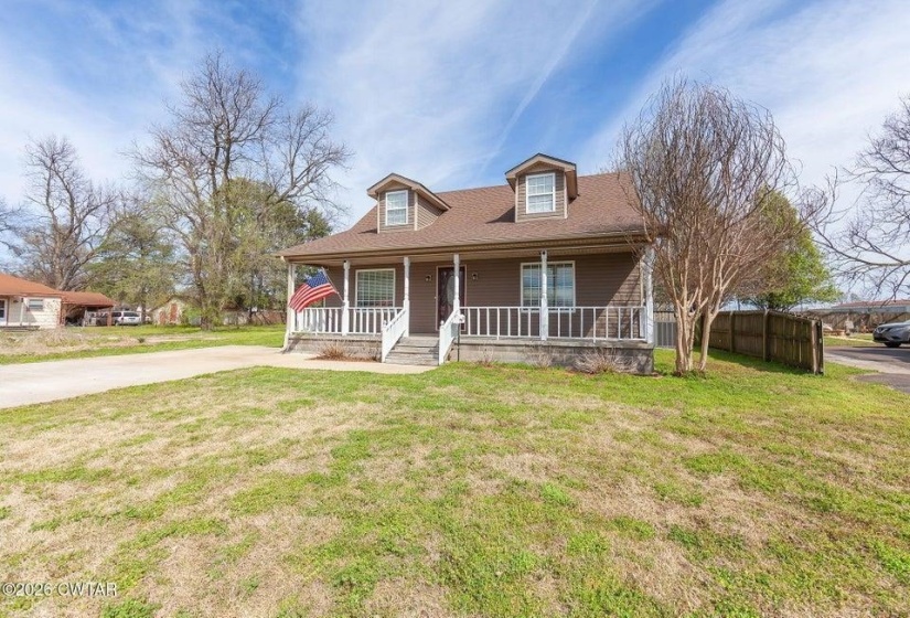 View of front of property with covered porch, a front lawn, and a shingled roof