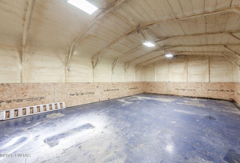 Miscellaneous room with unfinished concrete flooring and lofted ceiling