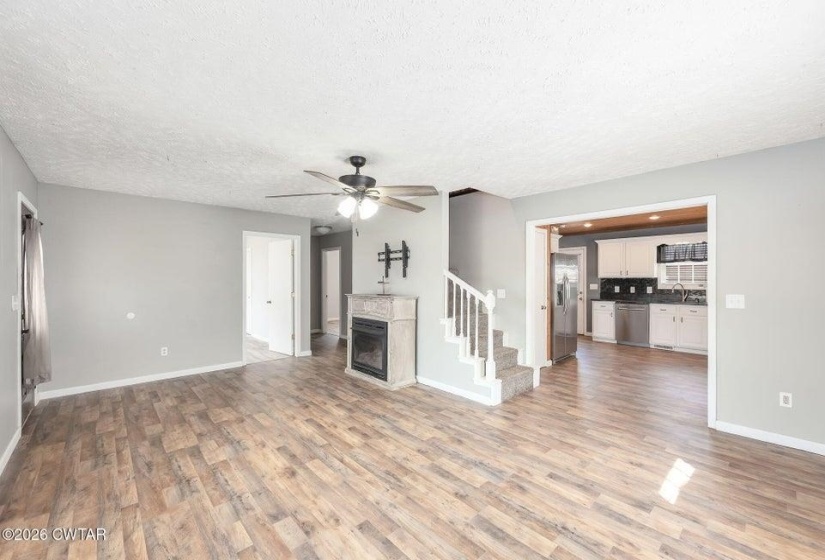 Unfurnished living room featuring light wood-style floors, a ceiling fan, a textured ceiling, and a fireplace