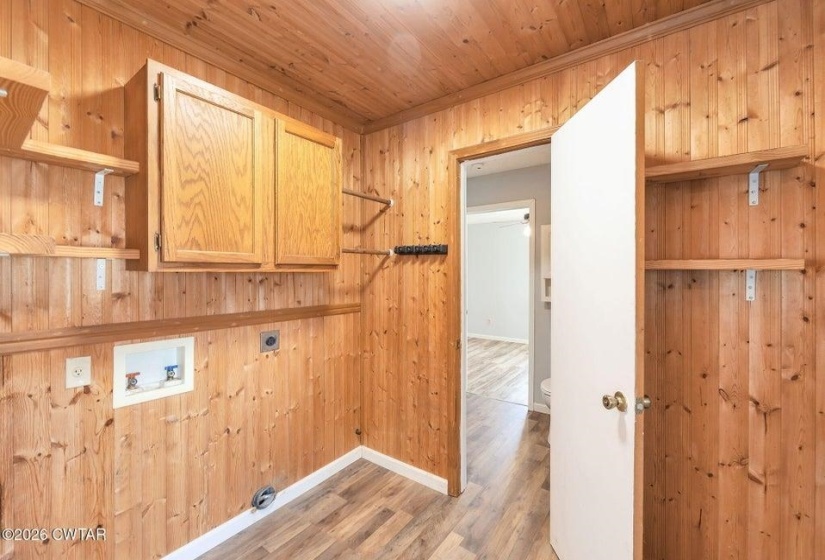 Laundry room with wood walls, cabinet space, light wood-style floors, hookup for an electric dryer, and hookup for a washing machine