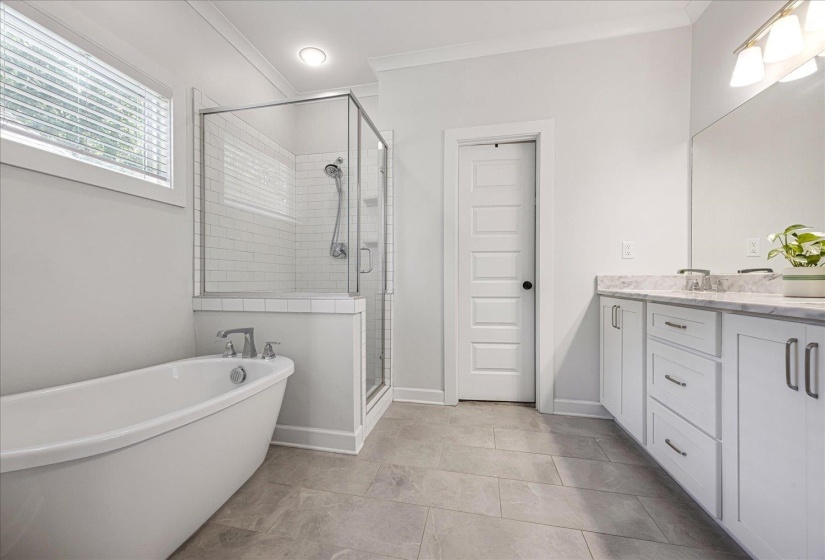 Full bath featuring vanity, a freestanding tub, a shower stall, crown molding, and light tile patterned floors