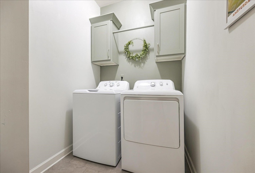Laundry room with washer and clothes dryer, light tile patterned floors, and cabinet space