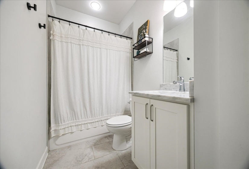 Bathroom featuring shower / bath combo, vanity, and light tile patterned flooring