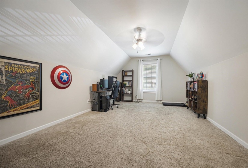 Additional living space with carpet flooring, vaulted ceiling, a ceiling fan, and a desk