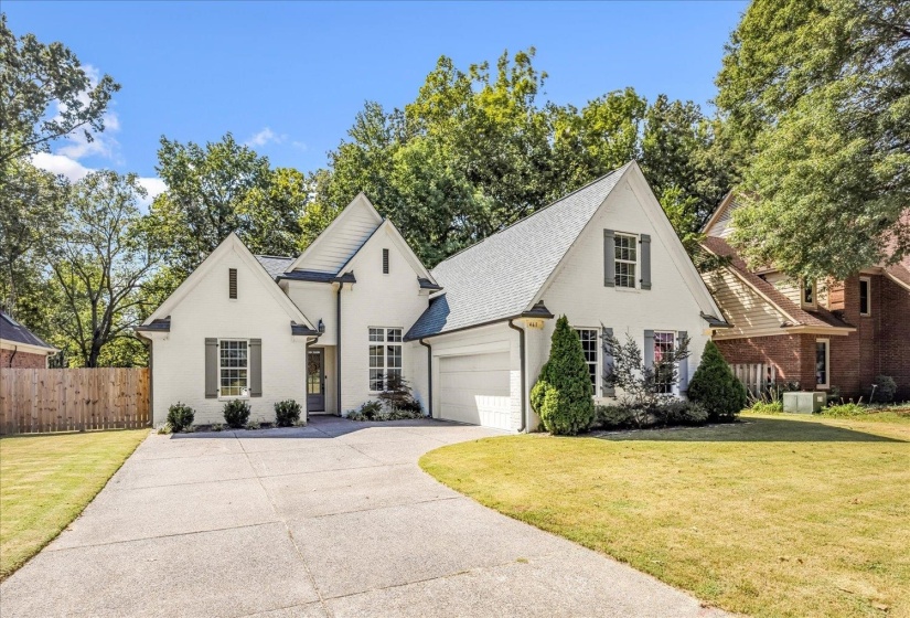 Traditional home featuring driveway, brick siding, and a garage