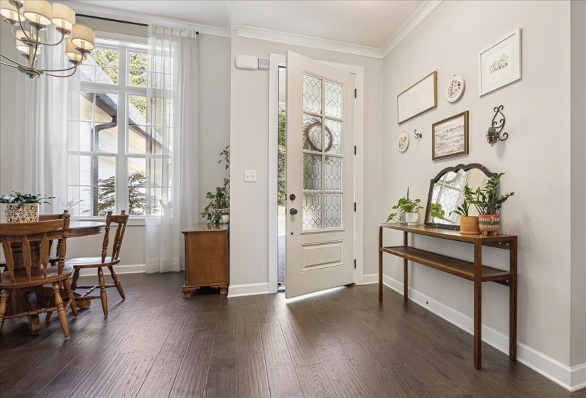 Doorway to outside with crown molding, wood finished floors, and a chandelier