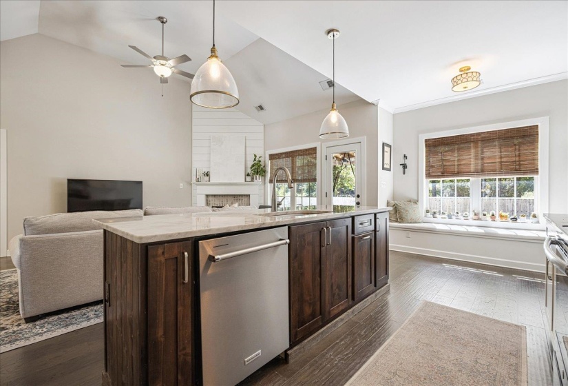 Kitchen featuring dark brown cabinets, appliances with stainless steel finishes, dark wood-style floors, open floor plan, and vaulted ceiling