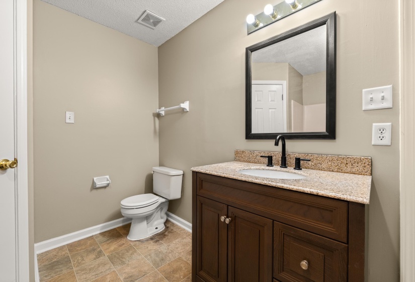 Bathroom featuring a dark wood vanity with a granite countertop, undermount sink, and matte black faucet