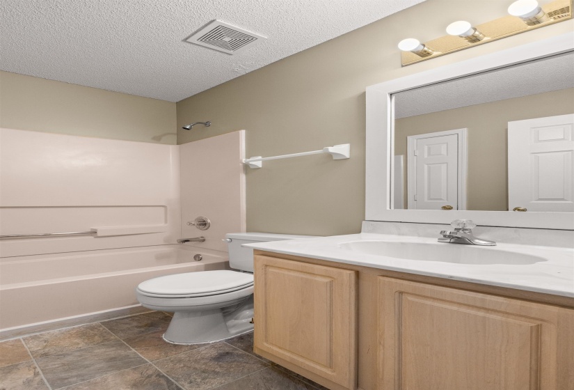 Full bathroom featuring a single vanity with wood cabinetry, a white countertop, and an integrated sink