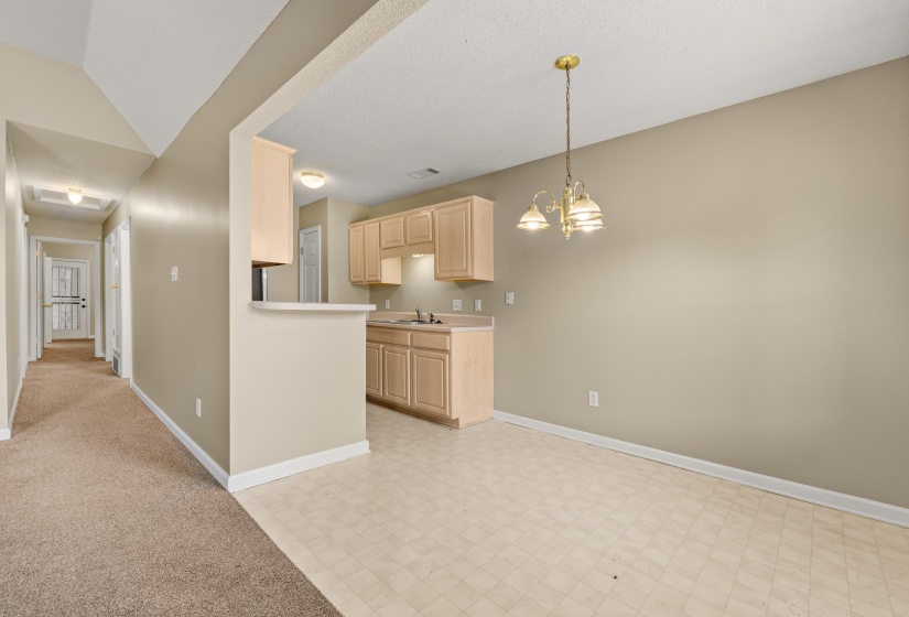 Kitchen area featuring light wood-finish cabinetry, a double basin sink, and a breakfast bar
