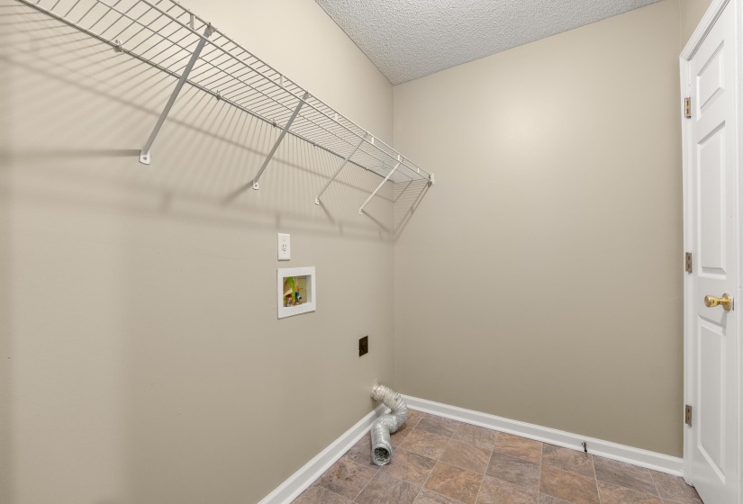 Utility room featuring neutral wall paint, wire shelving, and patterned flooring