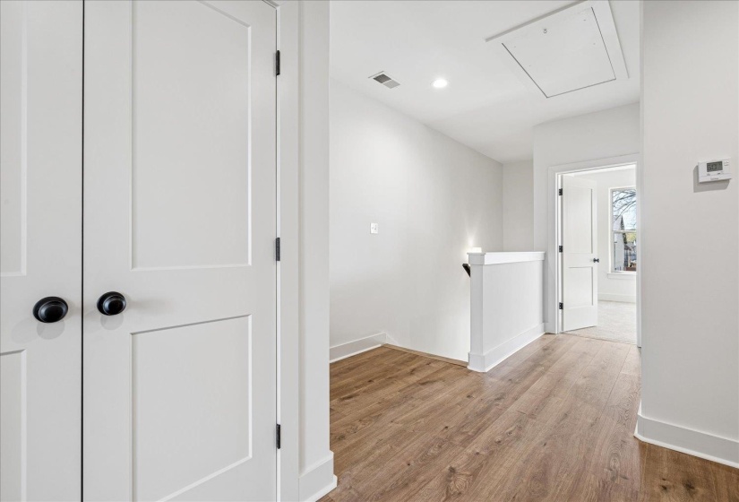 Hallway with an upstairs landing, light wood-style flooring, and recessed lighting