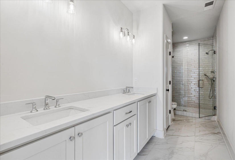 Bathroom with double vanity, a stall shower, light marble finish flooring, and recessed lighting