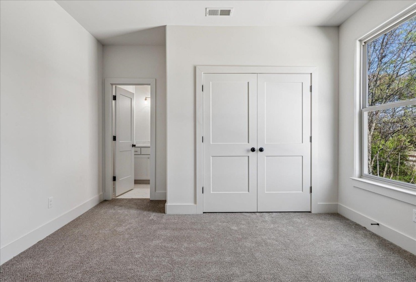 Unfurnished bedroom featuring carpet flooring, a closet, and ensuite bath