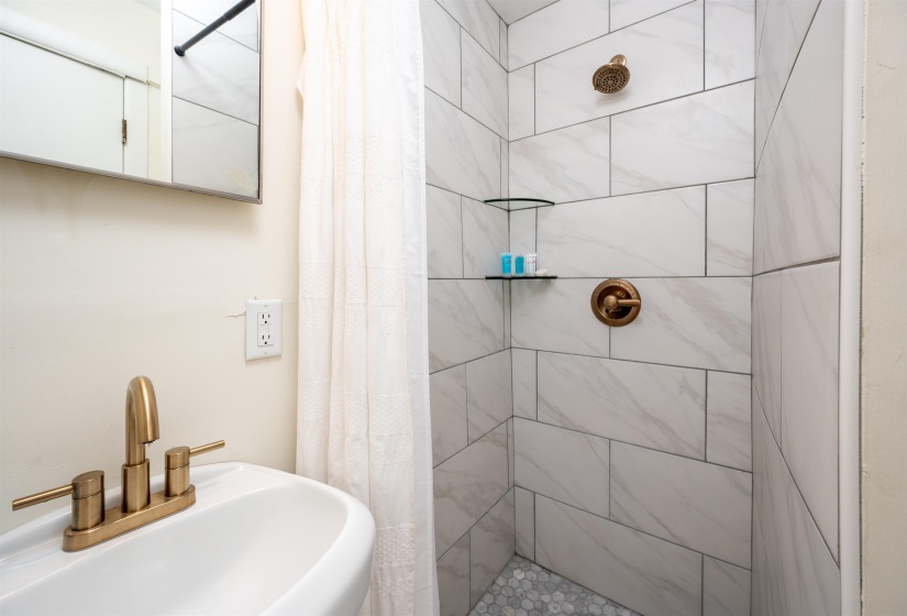 Shower with large format white wall tiles and bronze fixtures