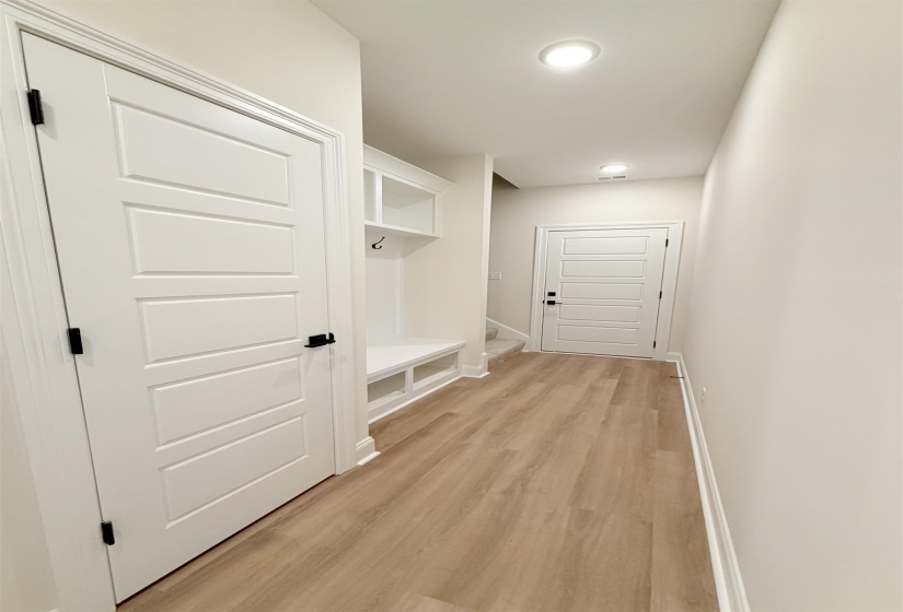 Mudroom entry featuring built-in storage, bench seating, and wood-finish flooring