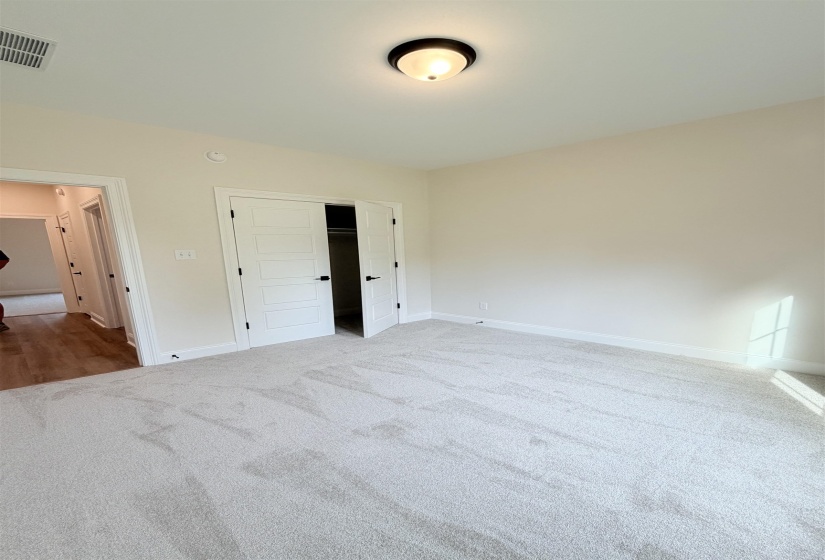 Spacious room featuring light gray carpeting, neutral wall paint, and white trim