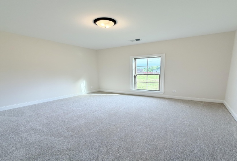 Spacious room featuring new gray carpeting, neutral-toned walls, and a large window with white trim