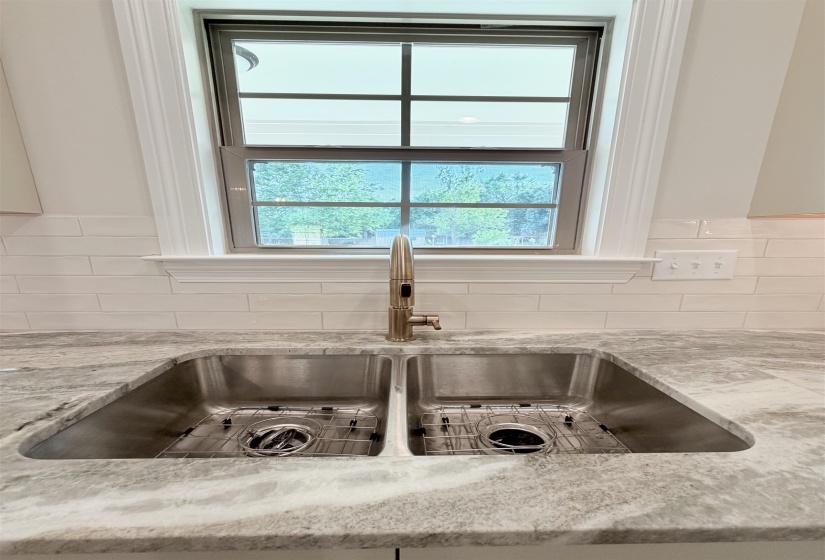 Stainless steel double basin sink with protective grates set into a patterned stone countertop