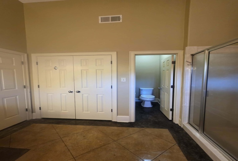 Bathroom featuring a glass-enclosed shower, a private water closet, and dual bifold closet doors