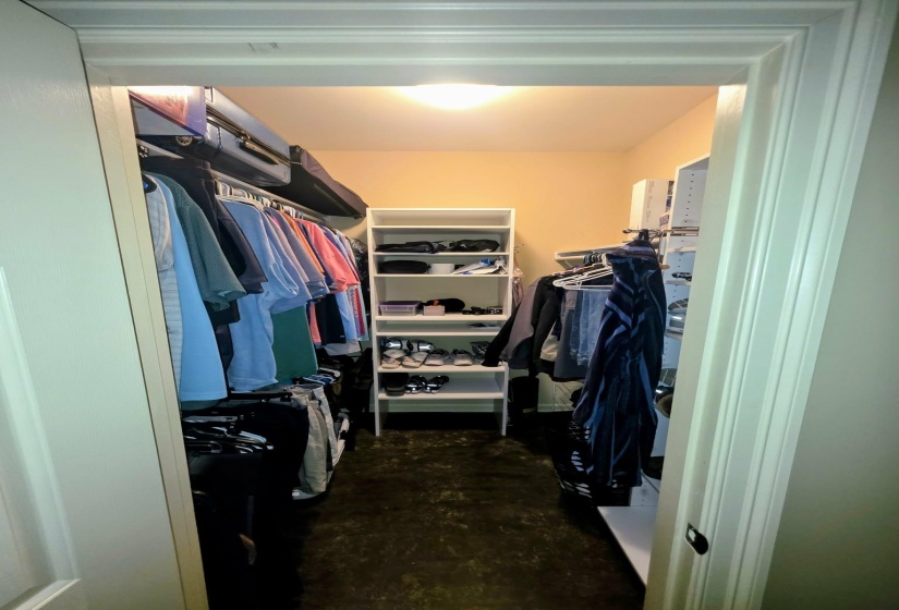 Walk-in closet featuring built-in shelving, hanging rods, an overhead flush-mount light fixture, and a neutral wall color