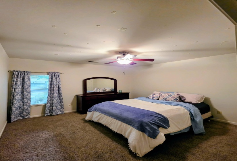 Carpeted room with a ceiling fan, window with blinds, and a built-in wall niche
