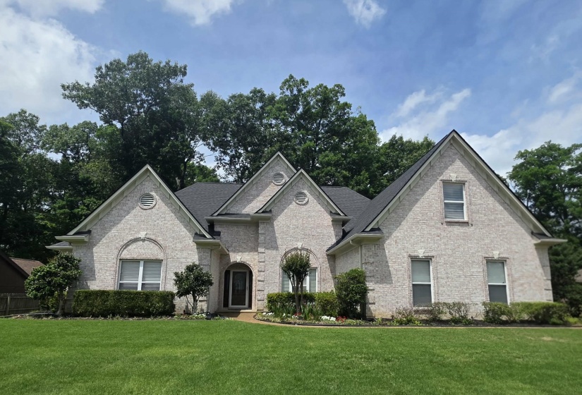 Light brick exterior with contrasting dark roof, featuring multiple gables and arched entryways
