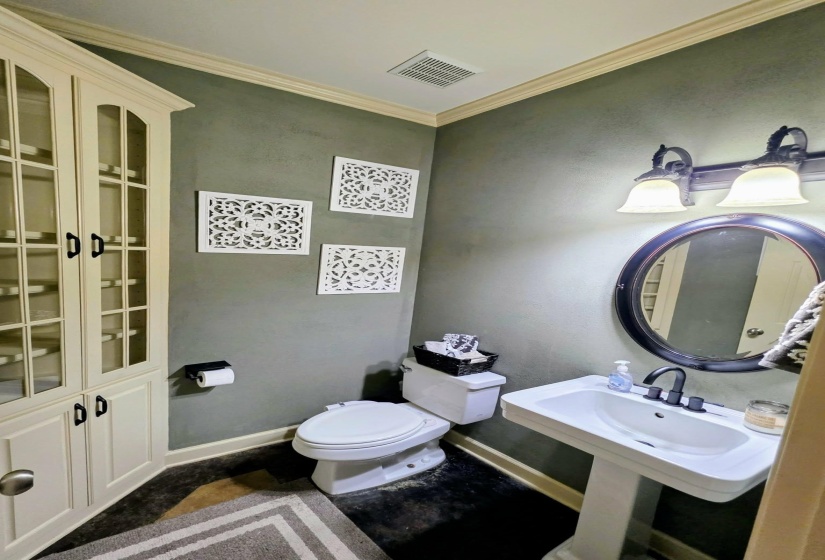 Pedestal sink with black faucet and round framed mirror