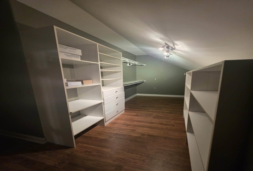 Custom closet system featuring white shelving units, integrated drawers, and ample hanging rod space