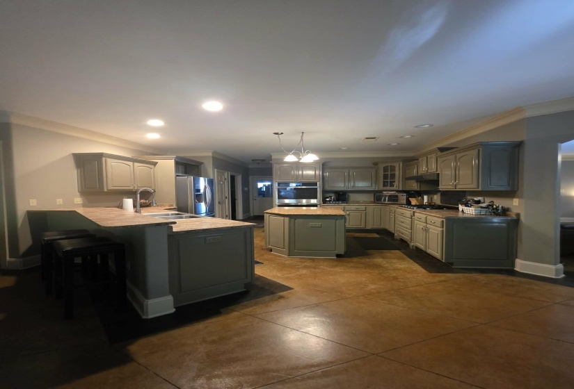 Spacious kitchen featuring painted cabinetry, an island, and a breakfast bar with built-in sink