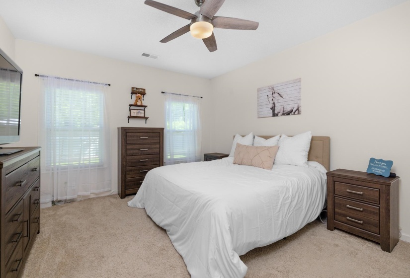 Carpeted bedroom featuring neutral wall tones and a ceiling fan with integrated lighting