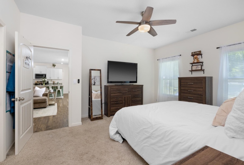Carpeted room with a ceiling fan light fixture, two windows with blinds, and white walls