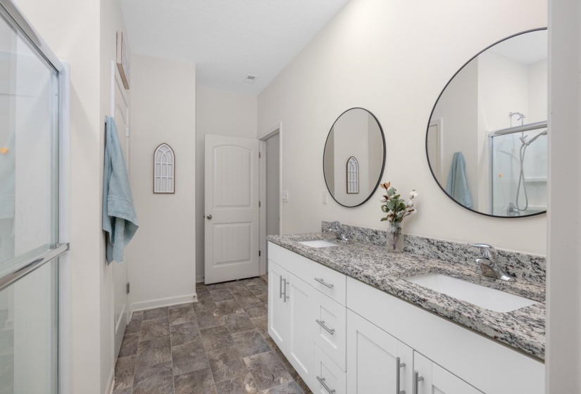 Dual vanity featuring white cabinetry, chrome hardware, and speckled countertops