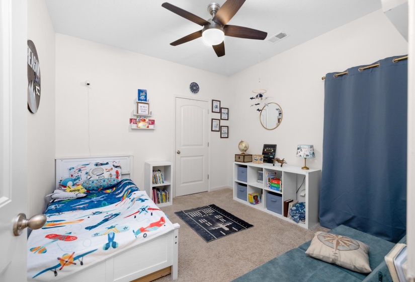 Carpeted bedroom featuring a ceiling fan with integrated lighting, white baseboards, and a paneled door