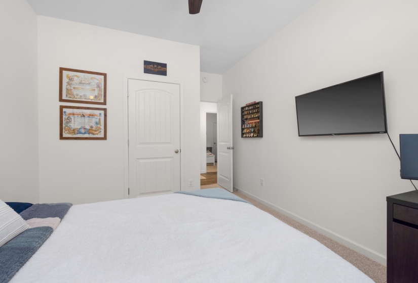 Bedroom featuring light neutral wall paint, a ceiling fan, carpet flooring, and a white paneled door