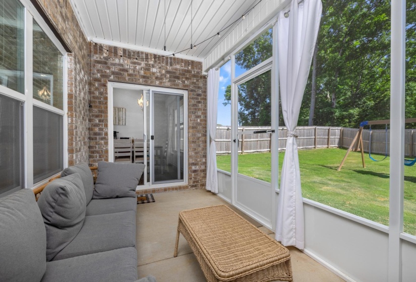 Screened porch featuring a brick exterior wall, concrete flooring, and a white beadboard ceiling